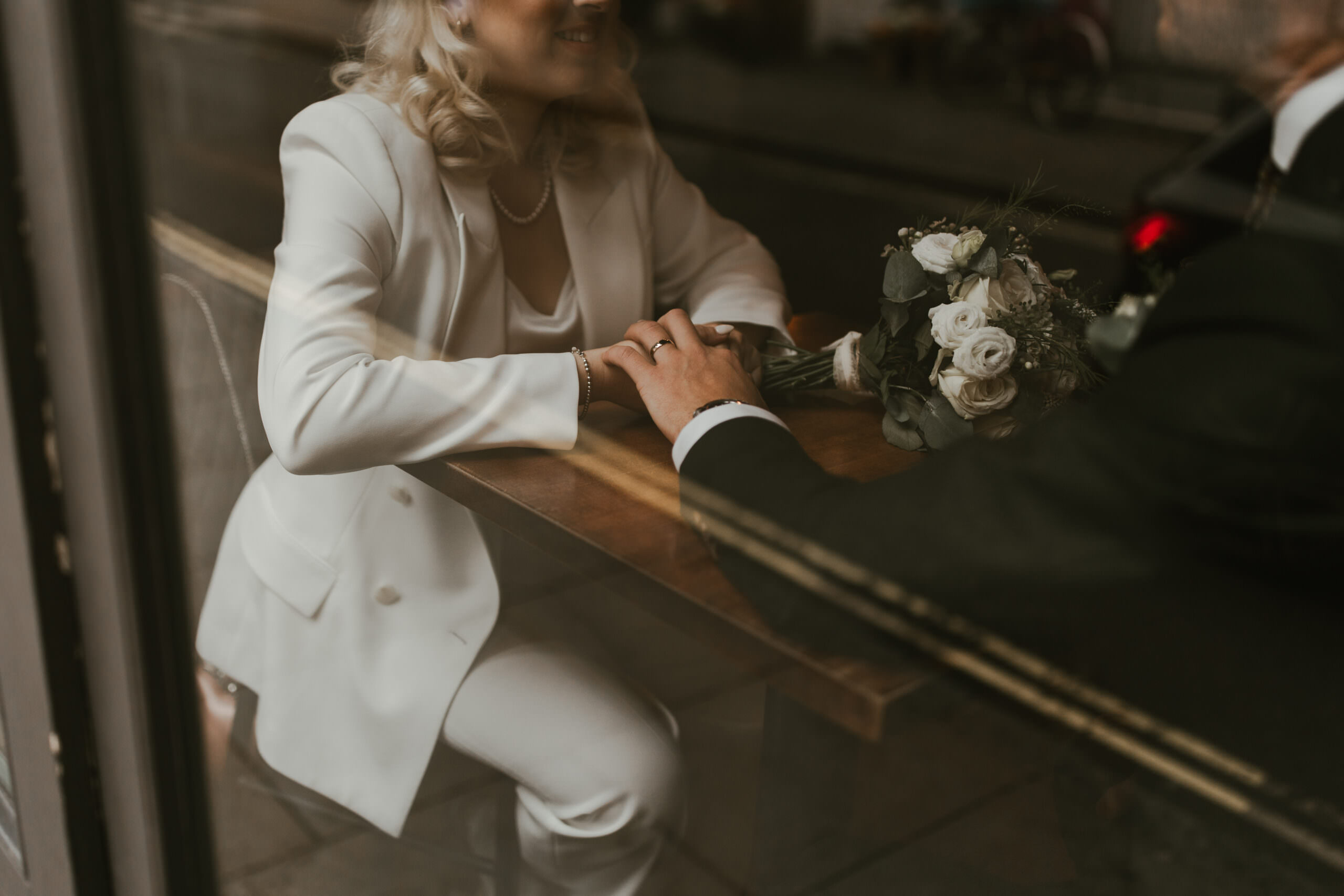 a newly married couple hold hands in a london pub window